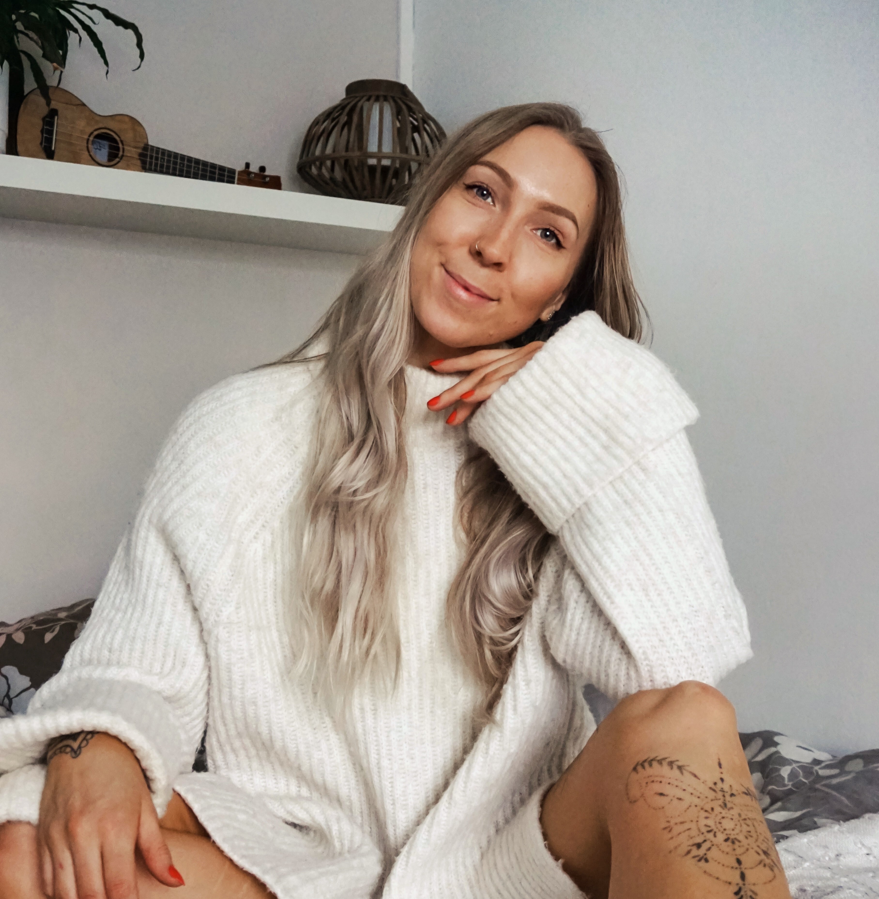 Nainen, jolla on valkoinen villapaita, katsoo kameraan